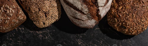Preview: Top View of Fresh Baked Whole Grain Bread on Stone Black Surface, Panoramic Shot