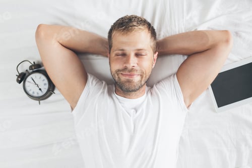 Man Relaxing in Bed Next to Tablet, Clock