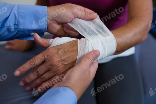 Preview: Physiotherapist putting bandage on injured hand of patient