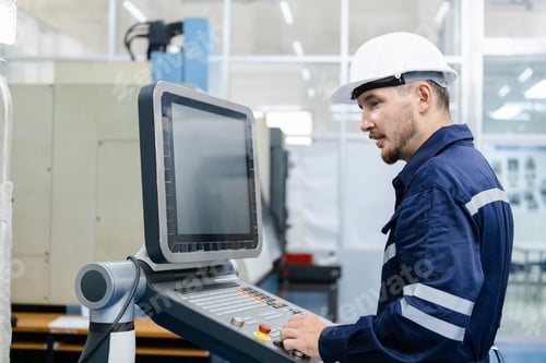 Preview: Man engineer using computer controlling cnc machine at workshop.