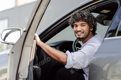 Preview: Indian smiling handsome man is smiling and opening door of his modern car