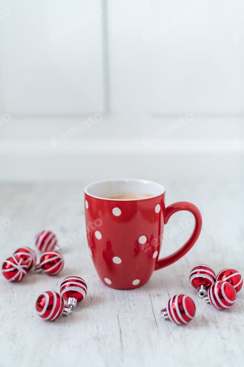 Preview: Selective focus shot of a cup of delicious hot coffee surrounded with red little Christmas balls