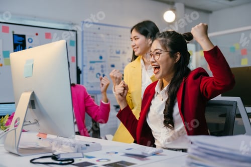 Preview: Three excited businesswomen are celebrating success in the office, raising their arms in front of a