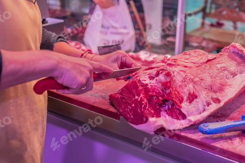Preview: Closeup of Female Butcher's Hand Cutting Beef Steak with Knife