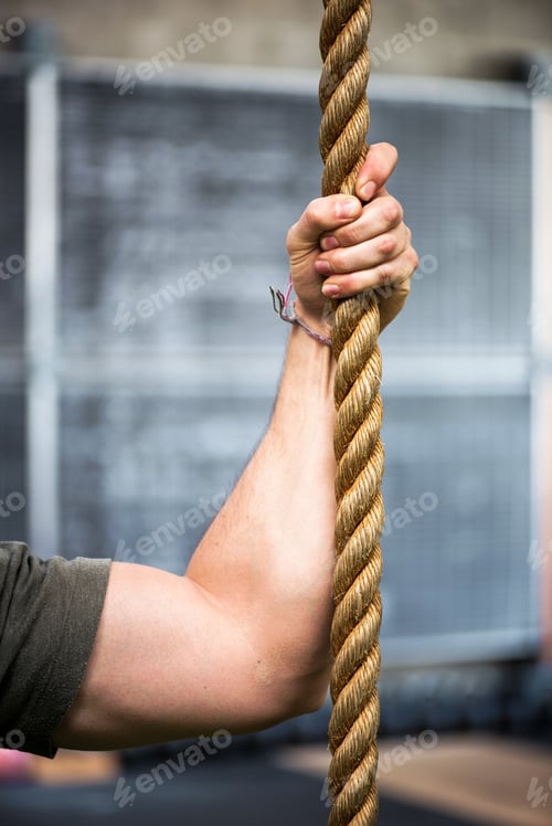 Preview: Strong muscular male arm holding a rope