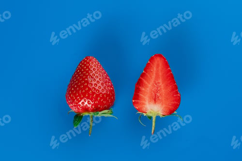 Preview: Strawberry slices and whole berries on blue background. Seasonal red fruit