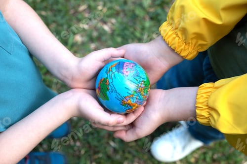 Preview: Children kid girl in a yellow raincoat and boy holding globe in a hands outdoor in park or forest