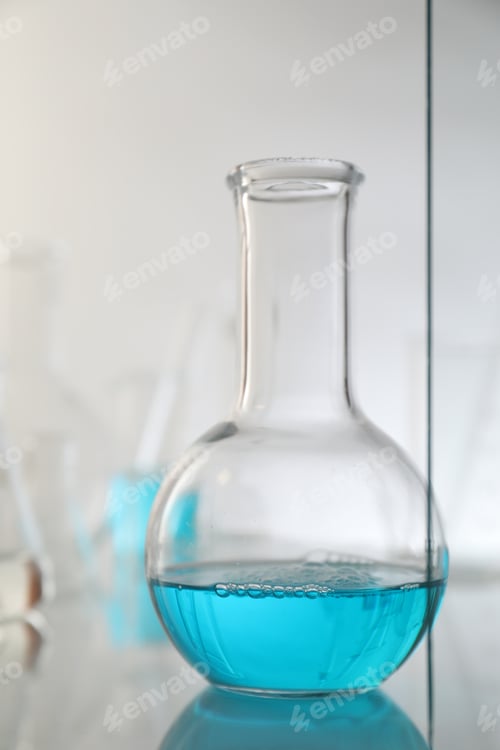 Preview: Flask with liquid on mirror surface against light background. Laboratory glassware