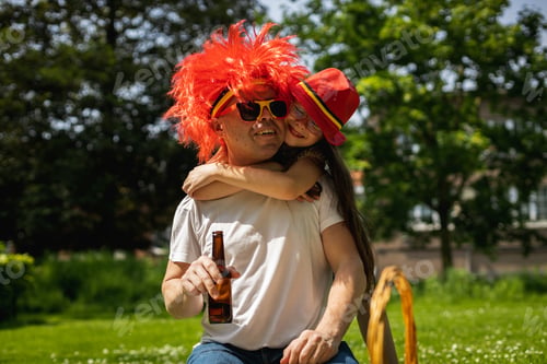Preview: Portrait of father with beer and hugging daughter celebrating belgian day.