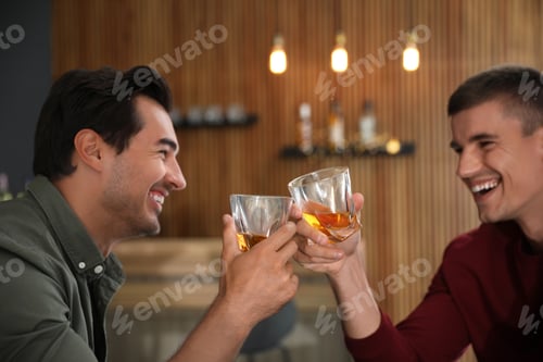 Preview: Young men drinking whiskey together in bar