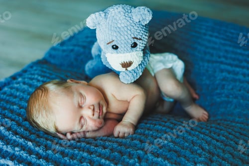 Preview: A newborn baby sleeps with a knitted teddy bear. Children's knitted toys. Baby sleep