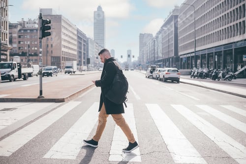 Preview: Young bearded caucasian man walking outdoor city crosswalk using smartphone