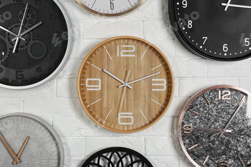 Preview: Different analog clocks hanging on white wall. Time of day