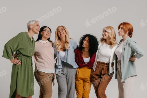 Preview: Multi-ethnic group of happy mature women embracing against grey background
