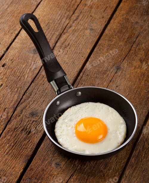 Fried Egg Cooking in a Pan on Wood