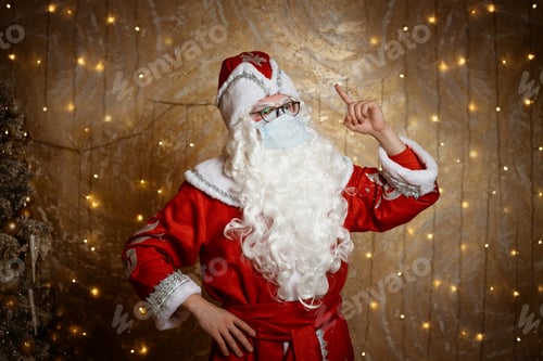 Preview: Santa Claus in glasses and a mask against a virus shows a hand gesture