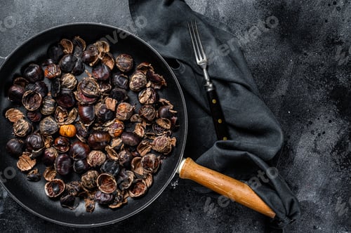Preview: Roast grilled chestnuts on a wooden table. Black background. Top view. Copy space