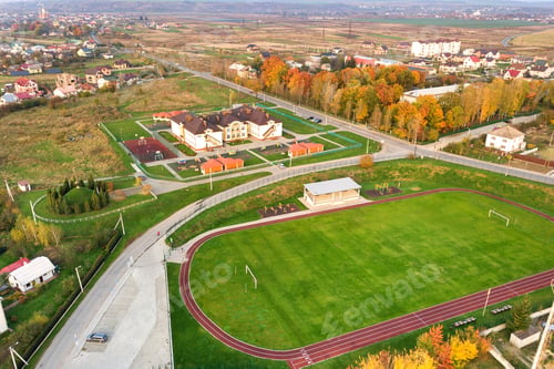 Preview: Aerial view of sports stadium with red running tracks and green grass football field.