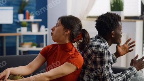 Preview: Irritated interracial couple getting into argument on sofa