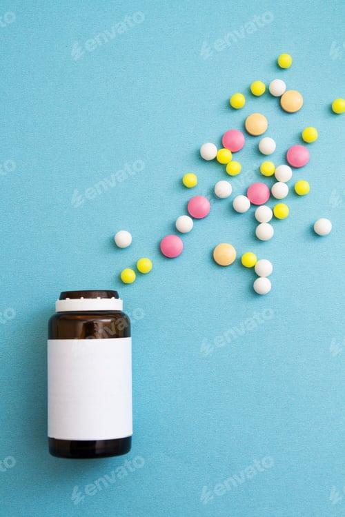 Preview: Different colors pills and shapes next to a bottle on blue background. Medical concept