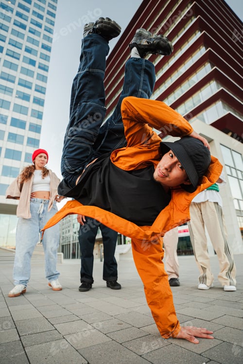 Preview: Energetic Breakdancer Showcasing a Skillful Freeze Move while Friends Support and Cheer him on