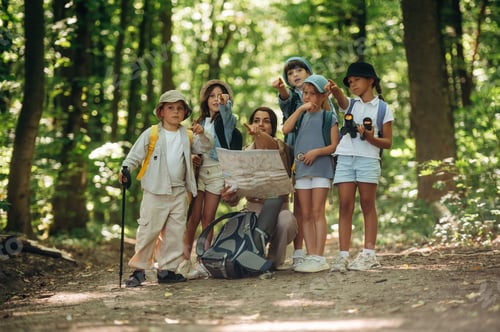 Preview: Path searching, sitting and reading a map. Woman is doing tour for group of kids in the forest