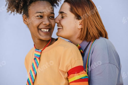 Preview: Smiling diverse lesbian couple embracing in studio