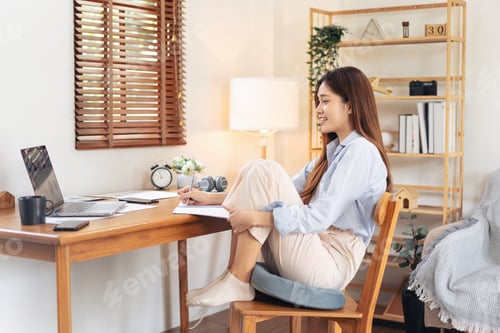 Preview: Female freelance is reading business data on laptop and writing