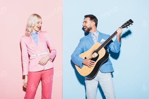 Preview: smiling woman and handsome man playing acoustic guitar on pink and blue background