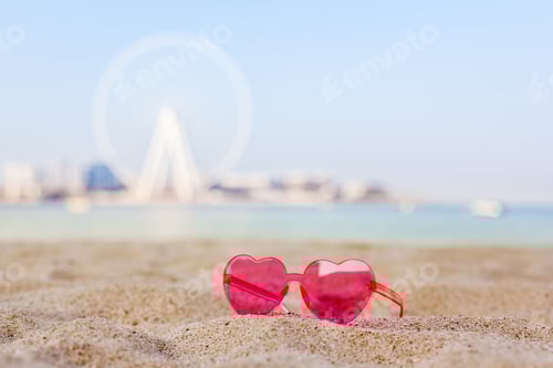 Preview: Pink sunglasses on a sandy beach with views of the Bluewaters Island