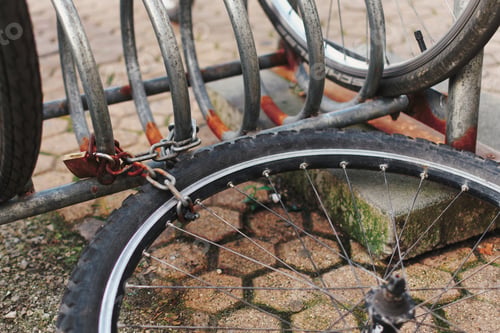 Preview: Wheel of a stolen bike chained to bicycle stand in city.