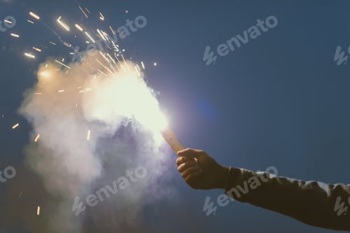 Preview: cropped view of male hand with smoke bomb with sparks at night