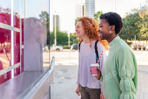 Preview: two young women smiling happy looking a showcase