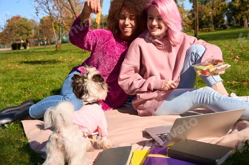 Preview: Two female students enjoying picnic on grass in park