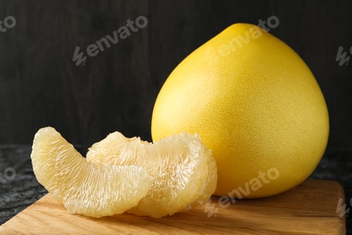 Preview: Board with ripe pomelo fruit on black smokey table