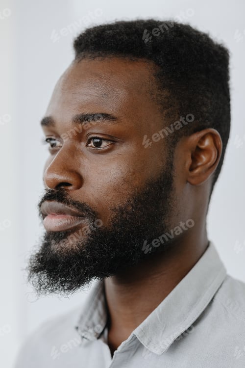 Preview: handsome young adult man with a beard and dark eyes looks thoughtfully away
