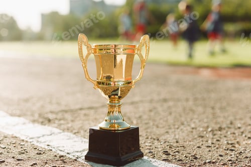 Preview: Football golden champion or winner cup with children football competition in background