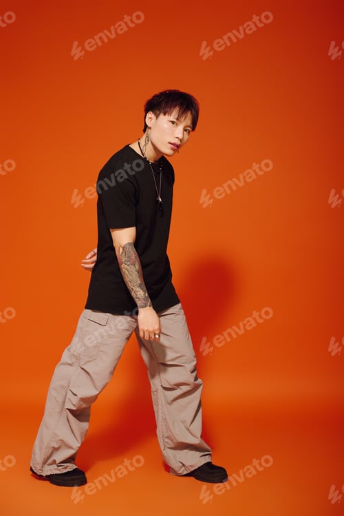 Preview: Handsome young man with trendy attire showcases his urban style in a striking orange backdrop