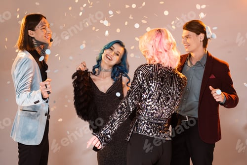 Preview: excited queer people in festive clothes dancing during christmas party on beige background