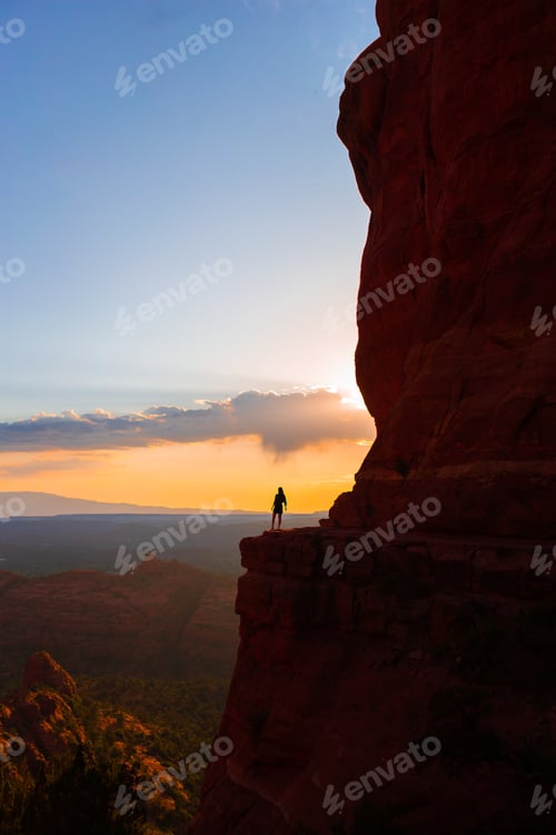 Preview: Silhouette of a woman on the trail at Cathedral Rock at sunset in Sedona. The colorful sunset over