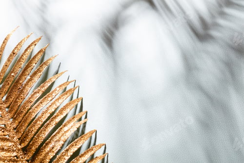 Preview: Gold palm leaves and shadows on a blue wall background.