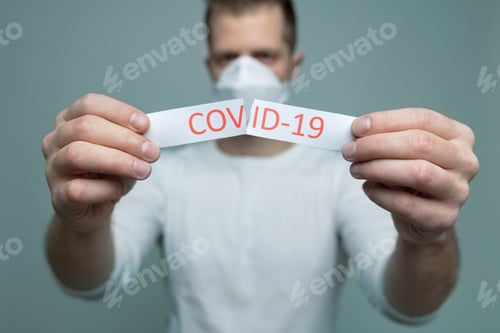 Preview: Man wearing a respiratory mask, holding the Coronavirus Covid-19 sign