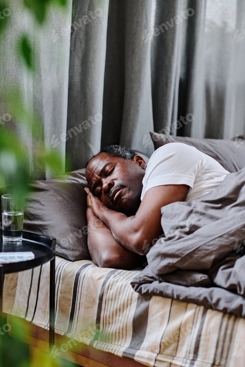 Preview: Tired mature African American man sleeping peacefully in bed in the morning