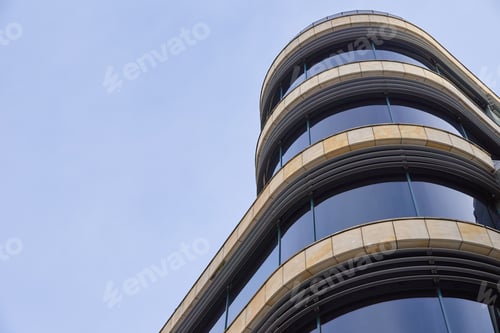 Preview: Modern glass building with curved facade against blue sky