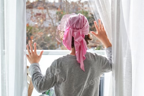 Preview: Anonymous kid in pink headband against glass door