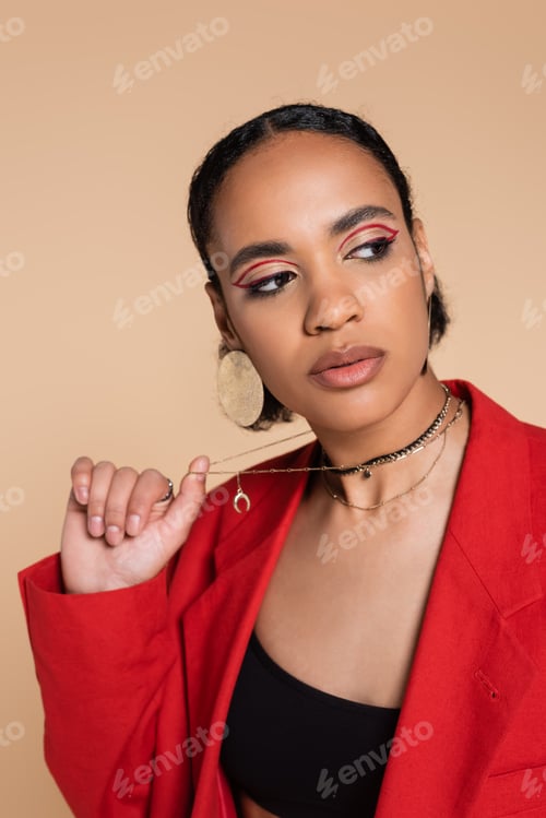 Preview: portrait of stylish african american model in bright red blazer pulling golden chain necklace