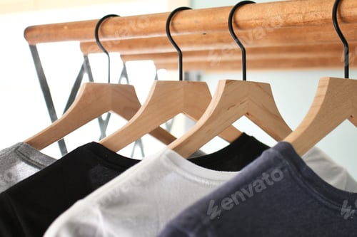 Preview: Simple basic t-shirts tee shirts hanging on wooden hangers in a laundry room on wash day.