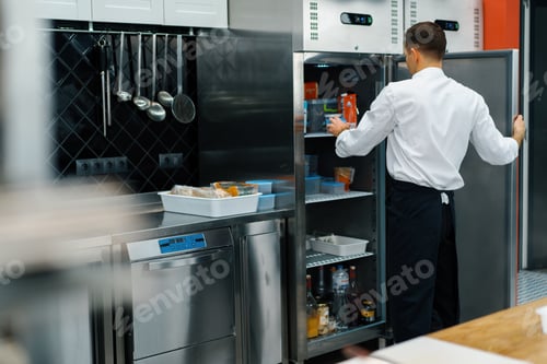 Preview: professional kitchen chef looks into the fridge and chooses ingredients for cooking food concept
