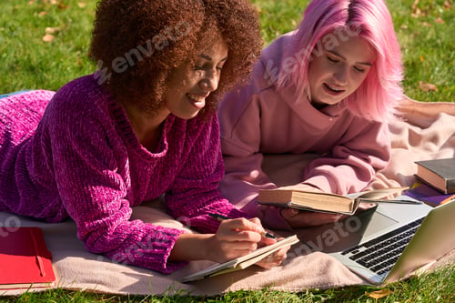 Preview: Two mixed-race female students doing homework outdoors