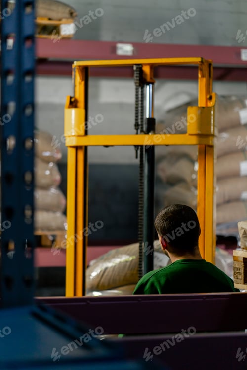 Preview: a worker at a coffee factory uses a yellow forklift to lift and place a pallet on shelf